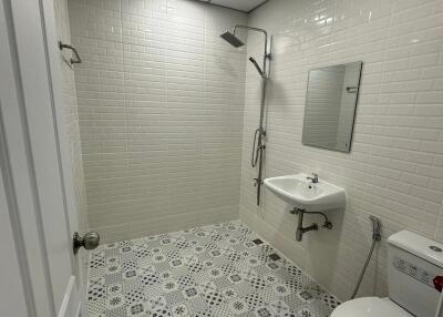 Modern bathroom with tiled walls and floor, shower, sink, and toilet