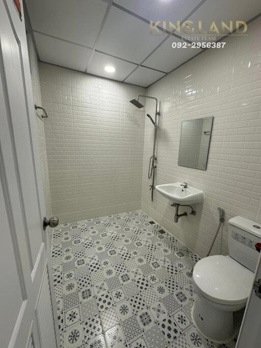 Modern bathroom with tiled walls and floor, shower, sink, and toilet