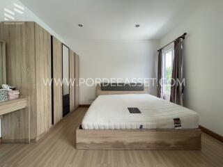 Modern bedroom with wooden flooring, large bed, and wardrobe