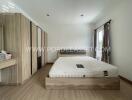 Modern bedroom with wooden flooring, large bed, and wardrobe