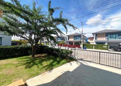 View of a residential neighborhood from a front yard with a tree and houses in the background