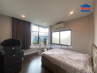 Bedroom with bed, air conditioner, large window, and stacked storage boxes.