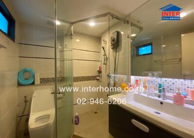 Modern bathroom with glass shower, toilet, and vanity.