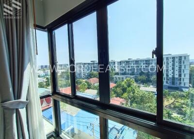 View through large windows overlooking buildings and greenery