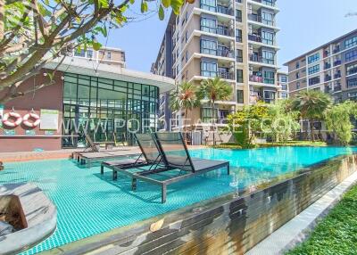 A modern apartment building with a swimming pool area surrounded by greenery.