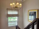 Well-lit staircase with a chandelier and a window