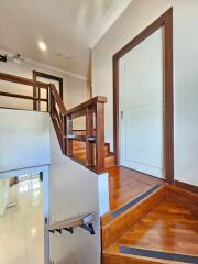 Indoor wooden staircase with white walls and a white door at the top landing