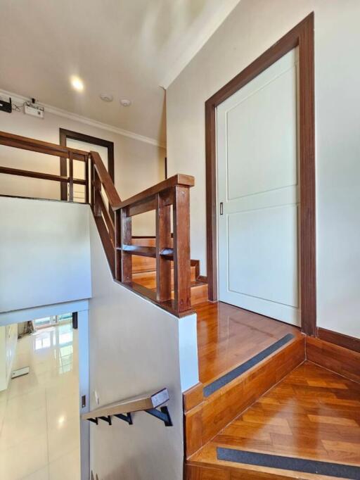 Indoor wooden staircase with white walls and a white door at the top landing