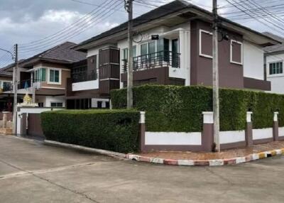 Exterior view of a modern two-story house with a well-maintained hedge and balcony