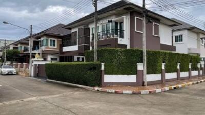 Exterior view of a modern two-story house with a well-maintained hedge and balcony