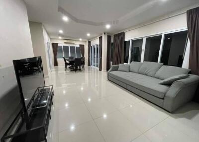 Spacious living room with a large sofa, dining area, and flat-screen TV