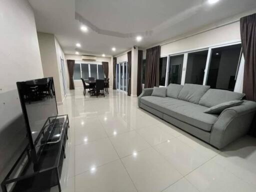 Spacious living room with a large sofa, dining area, and flat-screen TV