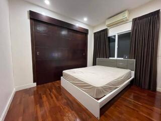 Spacious bedroom with wooden flooring, large bed, and built-in wardrobe