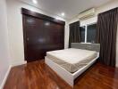 Spacious bedroom with wooden flooring, large bed, and built-in wardrobe