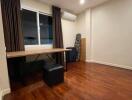 A bedroom with wooden flooring, desk and window