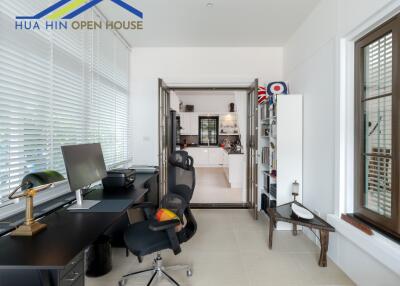 Home office area with desk, chair, and view into the kitchen