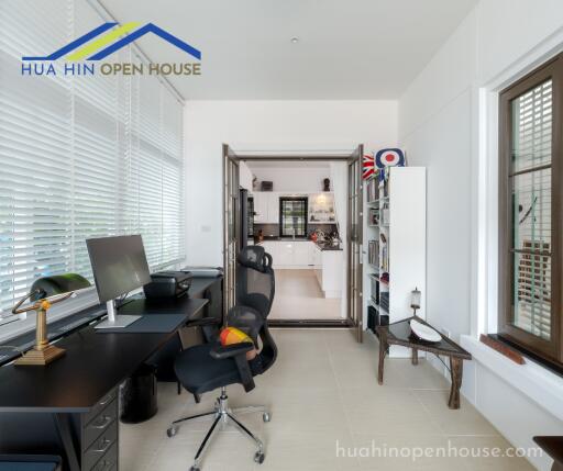 Home office area with desk, chair, and view into the kitchen