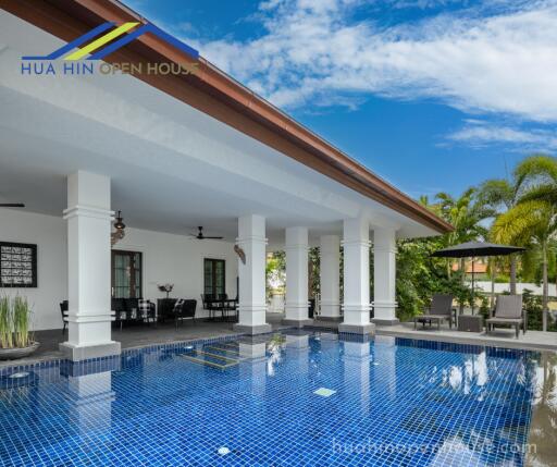 Outdoor swimming pool area with lounge chairs and covered patio