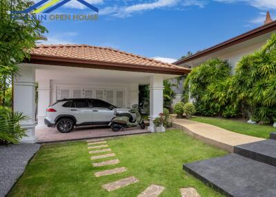 Covered garage with a car and a scooter in a modern house with a well-kept garden.