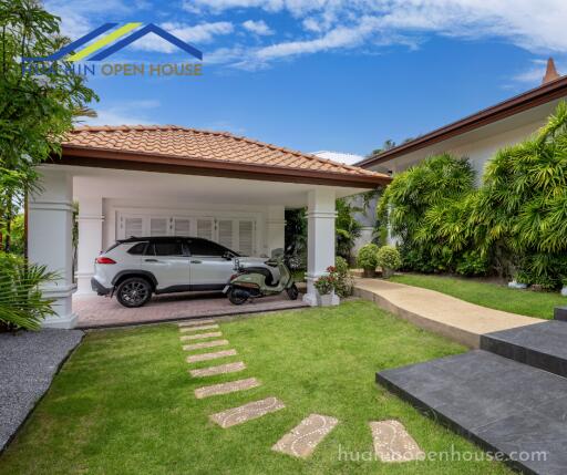 Covered garage with a car and a scooter in a modern house with a well-kept garden.