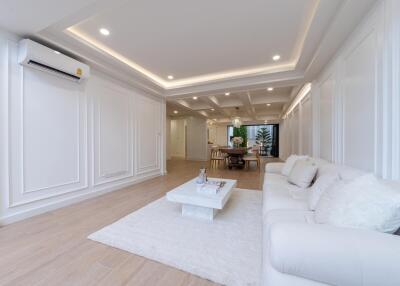 Modern living room with white interior, sofa, coffee table, and dining area in the background