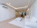 Modern living room with white interior, sofa, coffee table, and dining area in the background