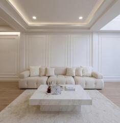 Elegant living room with beige couch, marble coffee table, and stylish wall paneling