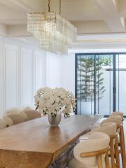 Dining room with wooden table, modern chandelier, and large windows