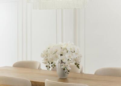 Dining room with wooden table, beige chairs, and chandelier