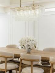 Dining room with wooden table, beige chairs, and chandelier