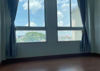 Empty bedroom with large windows, blue curtains, wooden flooring, and an air conditioner