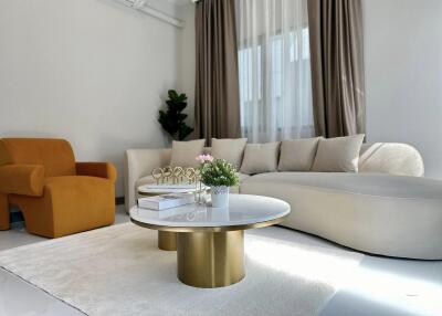 Modern living room with white couch, yellow chair, and gold-accented coffee tables