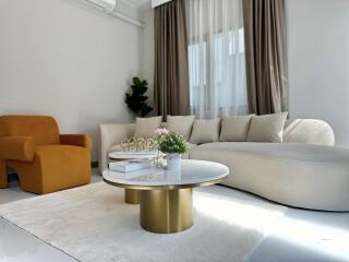 Modern living room with white couch, yellow chair, and gold-accented coffee tables