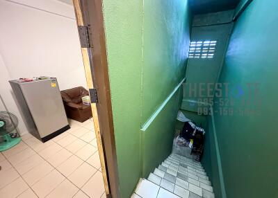 Staircase leading down with adjacent room containing a fridge and chair