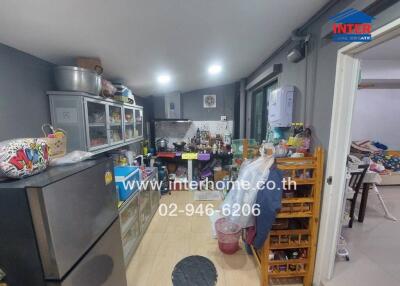 Cluttered kitchen with various appliances and furniture