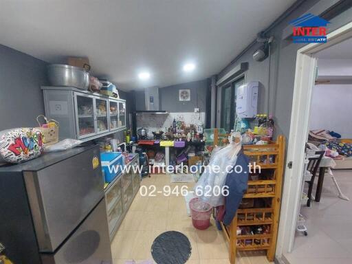 Cluttered kitchen with various appliances and furniture