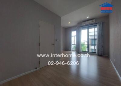 Spacious room with wooden flooring, large windows, and natural light