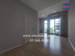 Spacious room with wooden flooring, large windows, and natural light