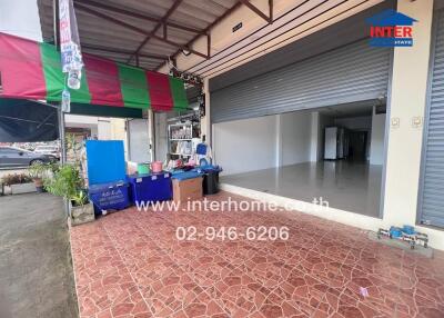 Exterior view of a building with a garage door and tiled floor in front.