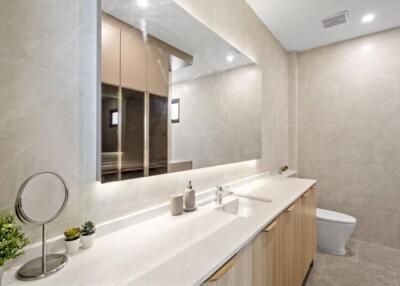 Modern bathroom with large mirror, sink, and toilet