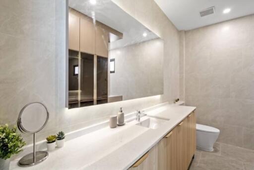 Modern bathroom with large mirror, sink, and toilet