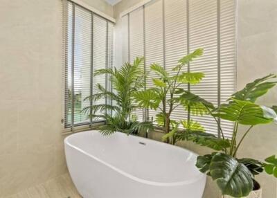 Modern bathroom with white bathtub and green plants