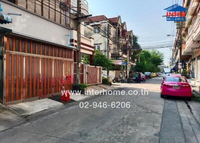 Street view of property with adjacent buildings and parked vehicles