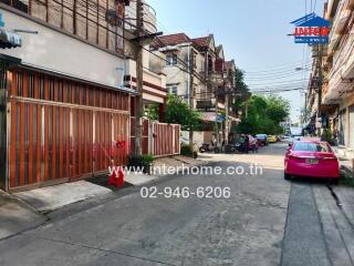 Street view of property with adjacent buildings and parked vehicles