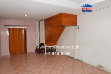 A living room with tiled floor and wooden stairs.