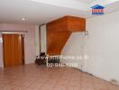 A living room with tiled floor and wooden stairs.