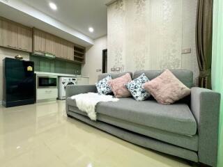 Cozy living room with a grey sofa and a small kitchen in the background