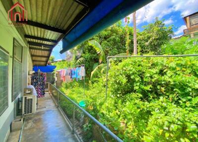 Covered walkway with view of lush greenery and a hanging clothesline