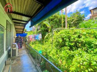 Covered walkway with view of lush greenery and a hanging clothesline