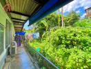 Covered walkway with view of lush greenery and a hanging clothesline